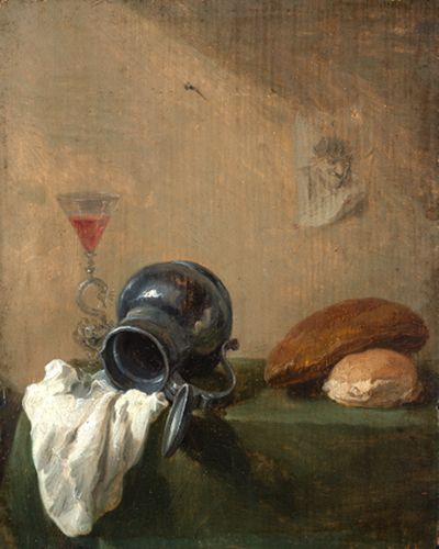 Auf dem Bild sieht man einen Tisch. Darauf stehen verschiedene Dinge: ein Zinnkrug (aus Metall), ein Glas, etwas Brot, Käse.