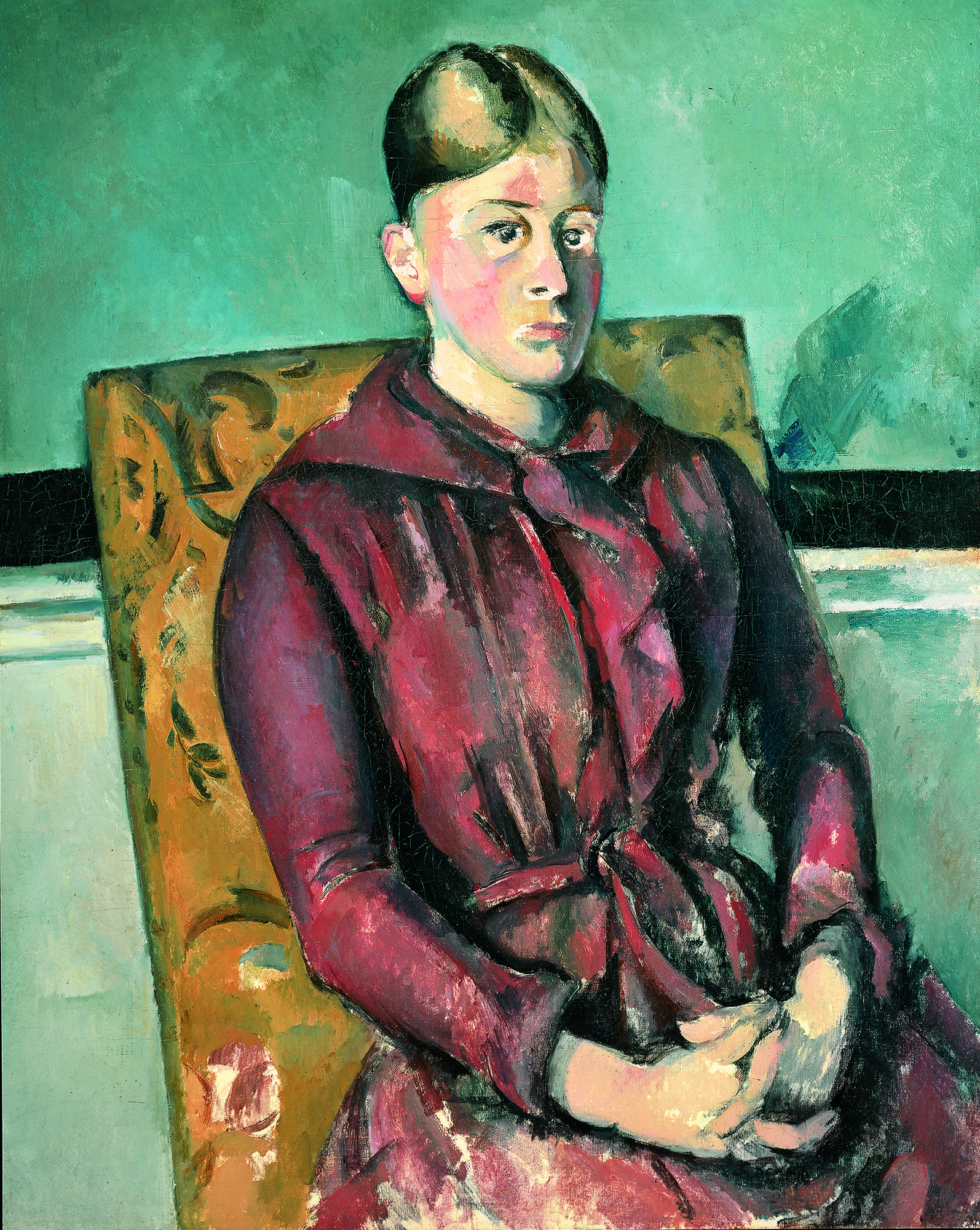 Das Werk Cézannes zeigt eine Frau im roten Kleid. Sie sitzt auf einem gelben Sessel. Der Raum ist türkis gefärbt.