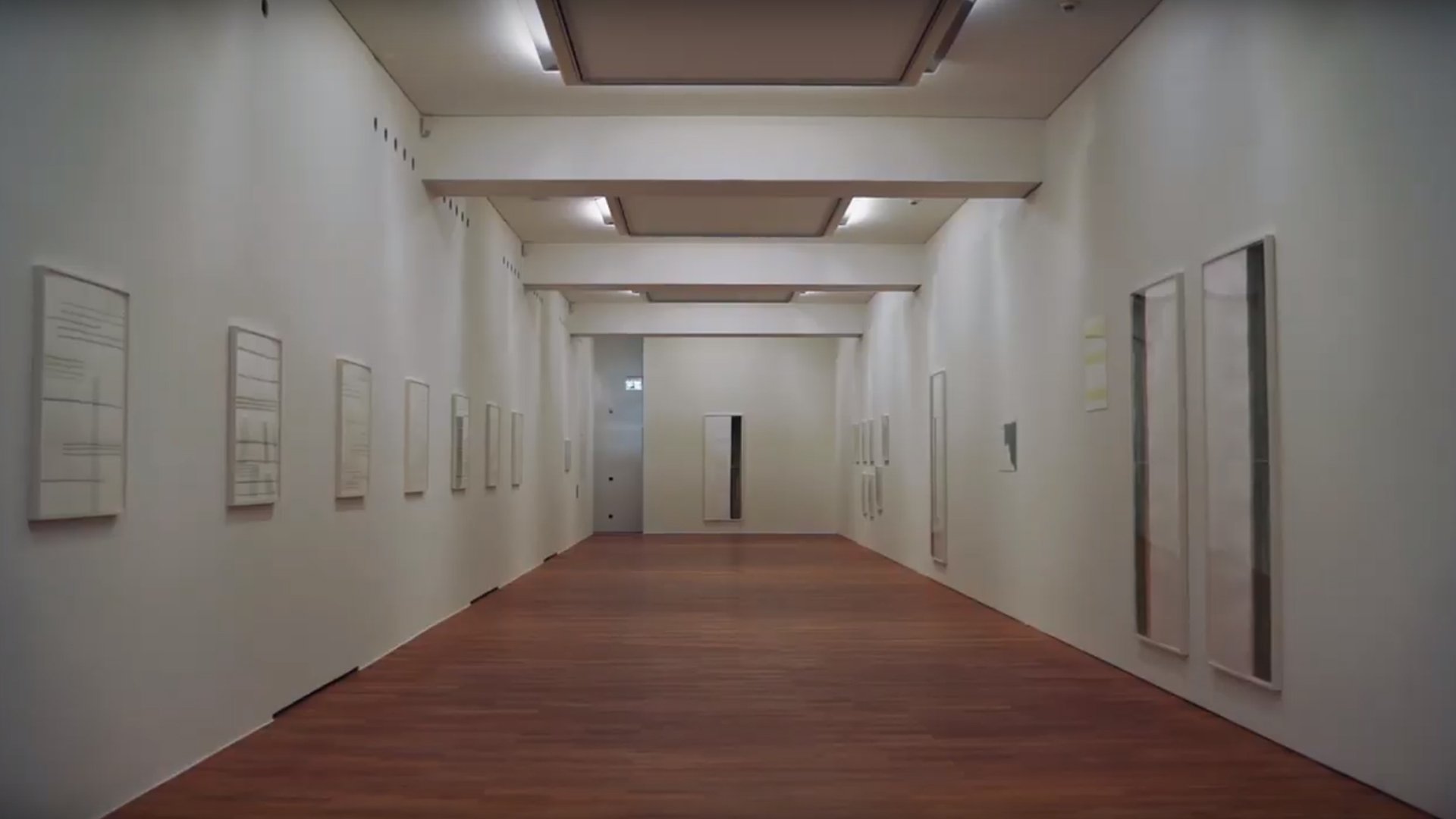 Film still from the exhibition teaser for "Silvia Bächli - shift! It shows a long exhibition room with works of art on the walls.