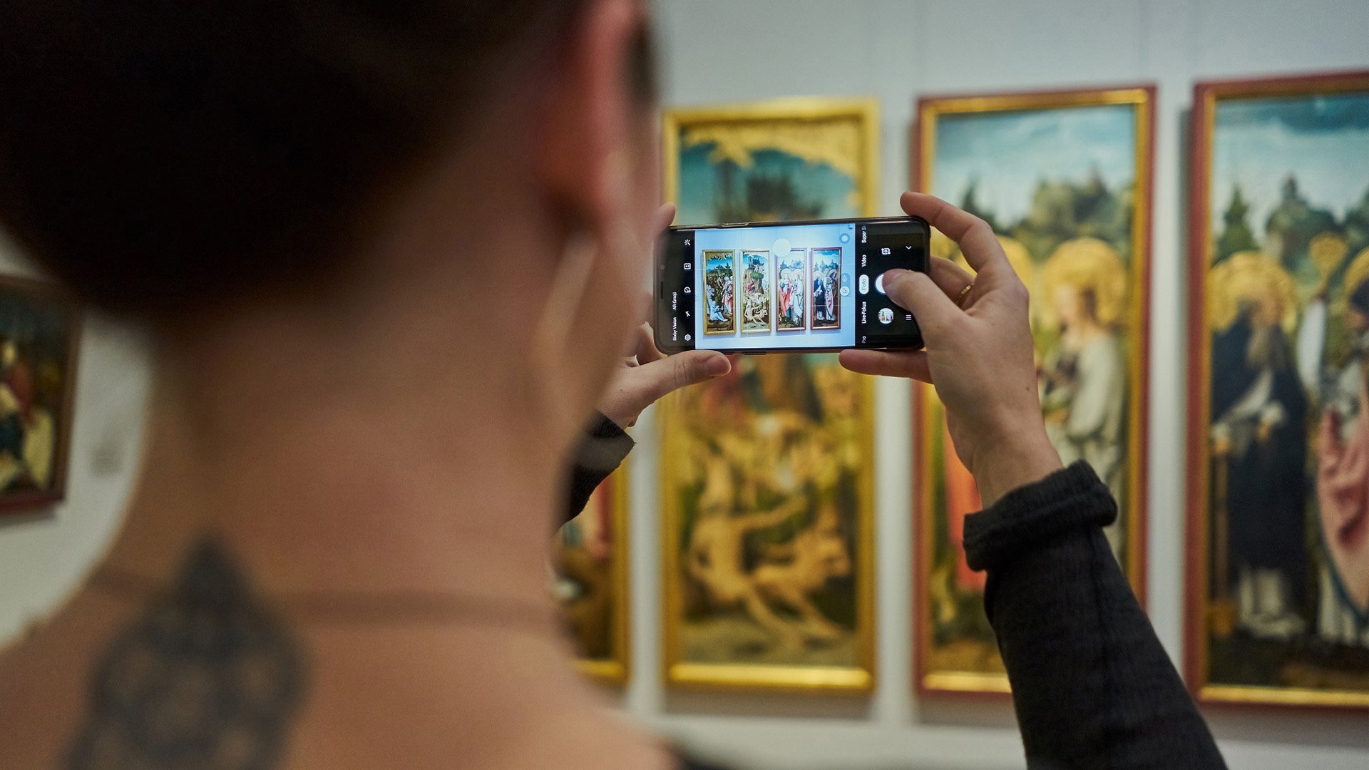 Foto einer Besucherin, die mit ihrem Smartphone ein Kunstwerk fotografiert.
