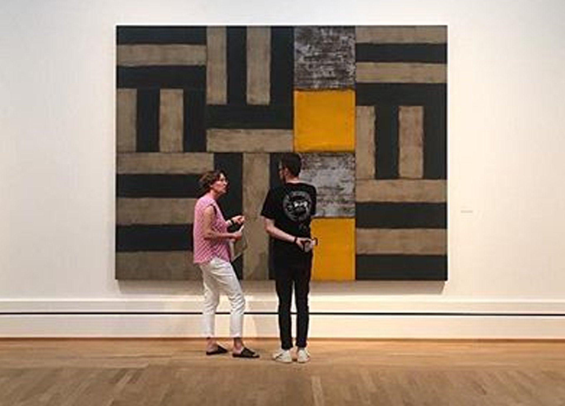 Zwei Personen stehen vor einem abstrakten großformatigen Gemälde Scullys und unterhalten sich.