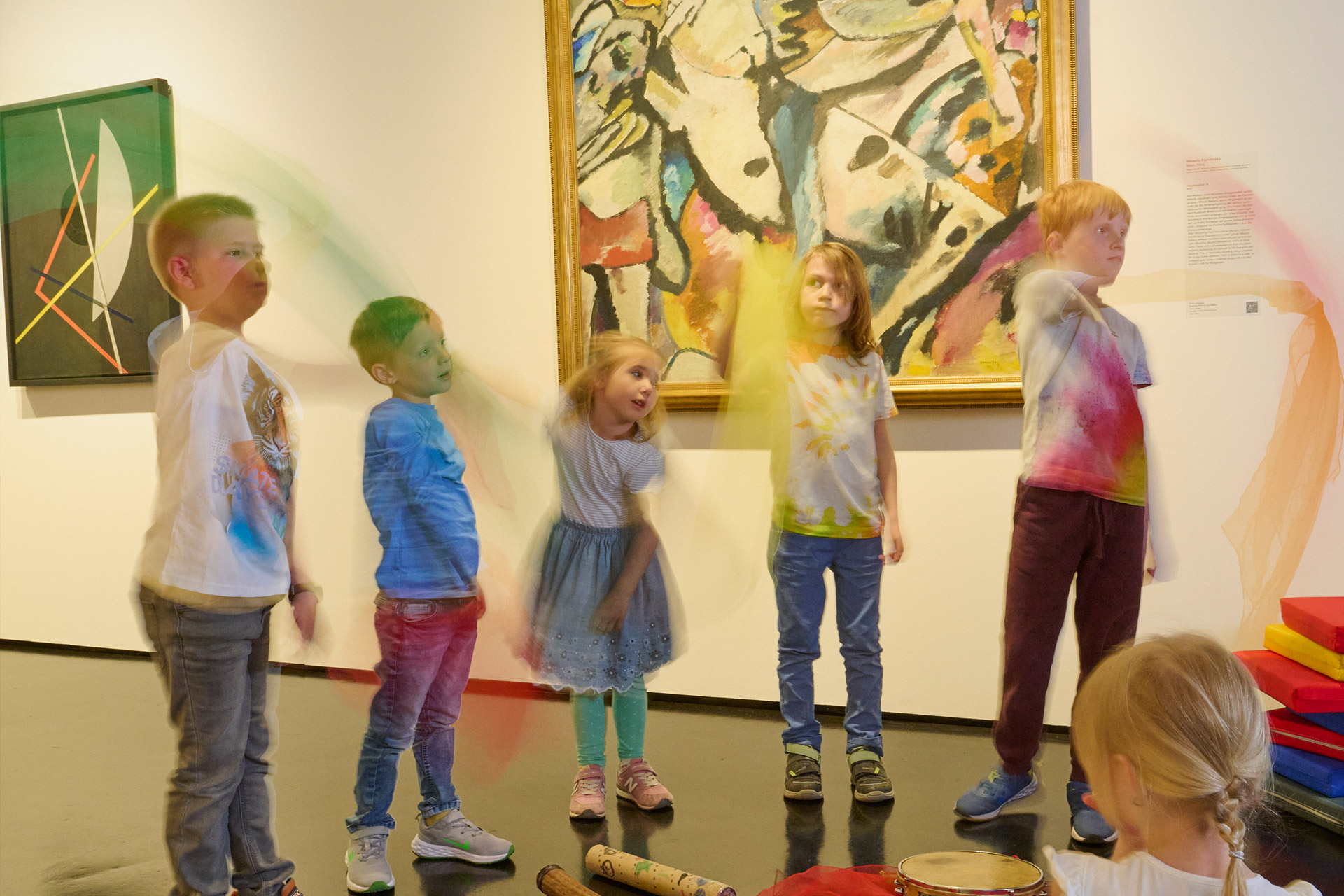 Mehrere Kinder stehen in der Ausstellung vor einem Werk von Kandinsky und schwingen mit Tüchern.