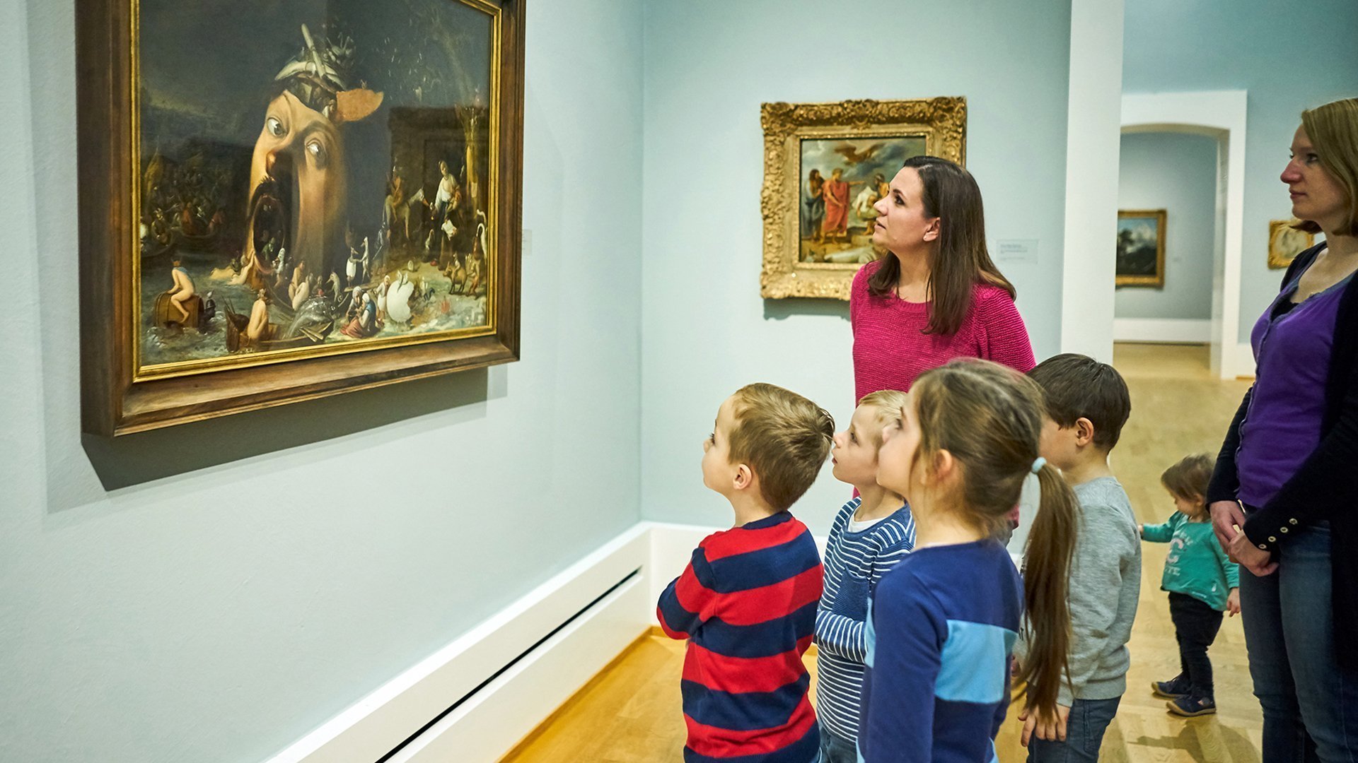 Foto eines Familienausflugs in die Sammlung der Kunsthalle. Erwachsene und Kinder stehen vor einem Gemälde und betrachten es.