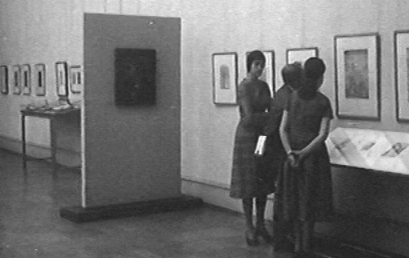 Blick in die Baldungausstellung 1959. Zu sehen sind drei Frauen, die ein Kunstwerk ansehen.