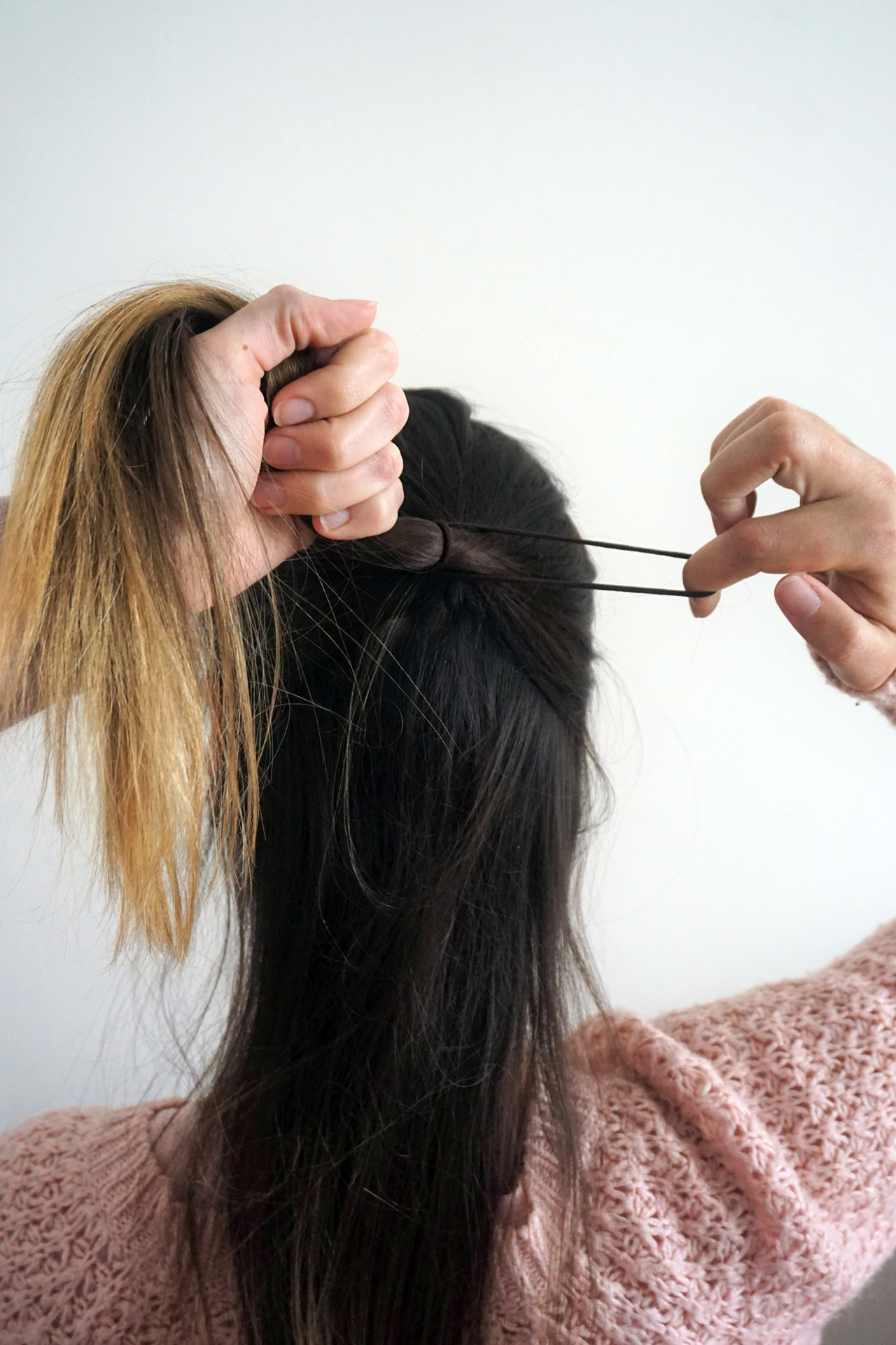 Das obere Drittel des Deckhaars mit einem Haargummi von der restlichen Haarpartie abteilen. Den Haargummi nur so oft um die Partie wickeln, bis er nur noch einmal herumgewickelt werden kann.