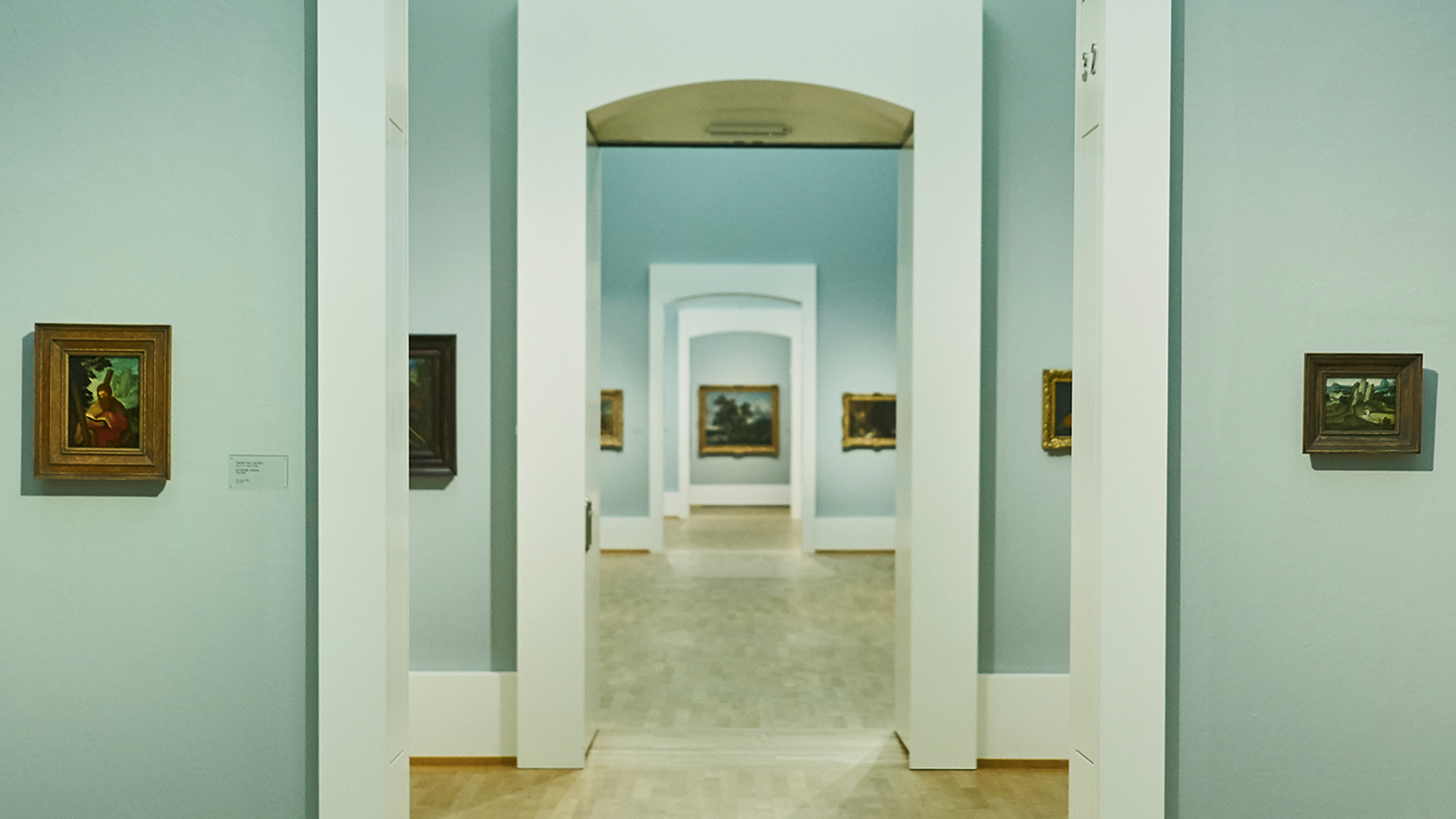 Blick in die Raumflucht der Kunsthalle Karlsruhe. Die Wände sind hellblau und es hängen Kunstwerke an den Wänden.