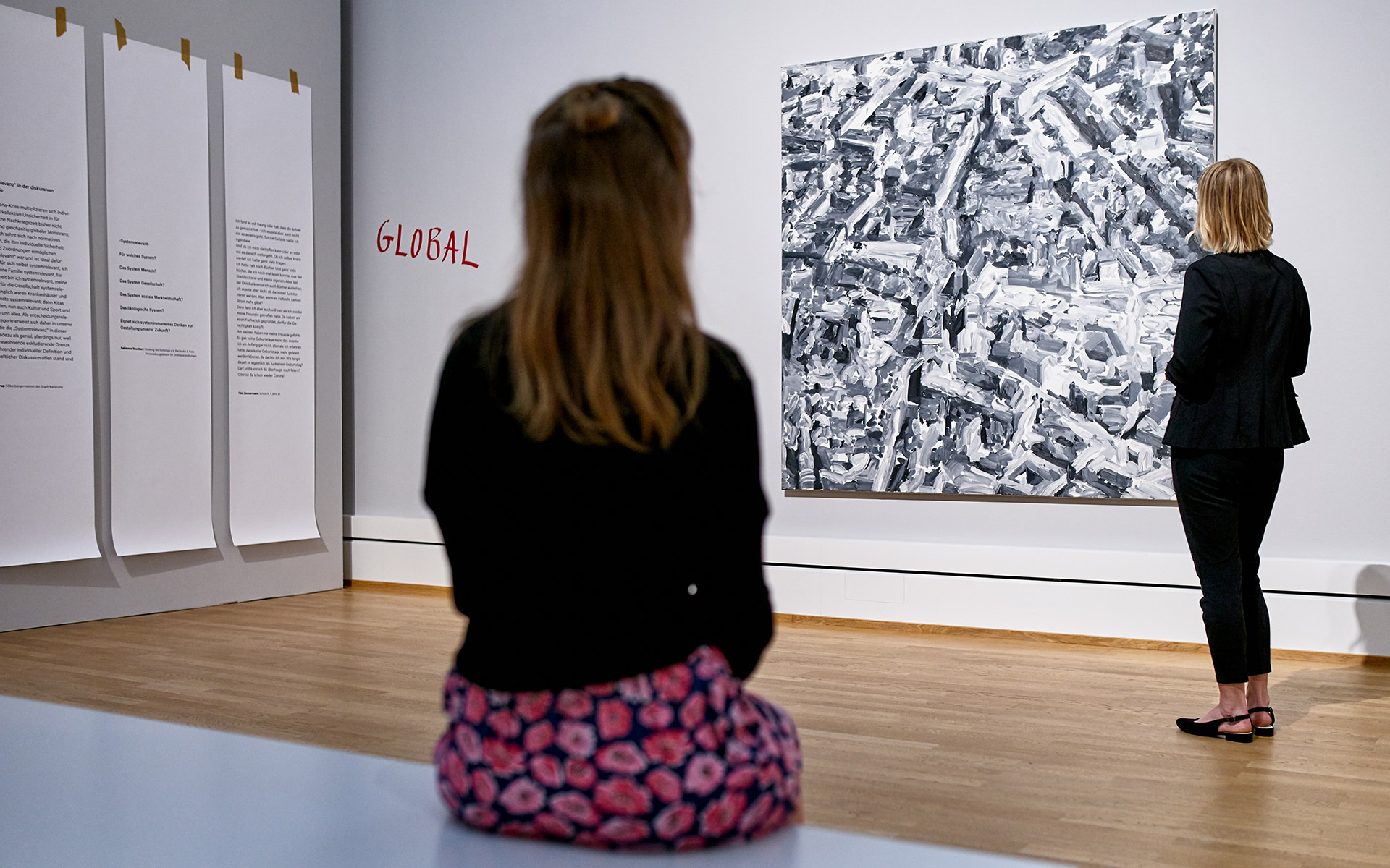 Ausstellungsansicht der Ausstellung Systemrelevant? in der Kunsthalle Karlsruhe. Zwei Frauen betrachten ein großformatiges abstraktes Gemälde.