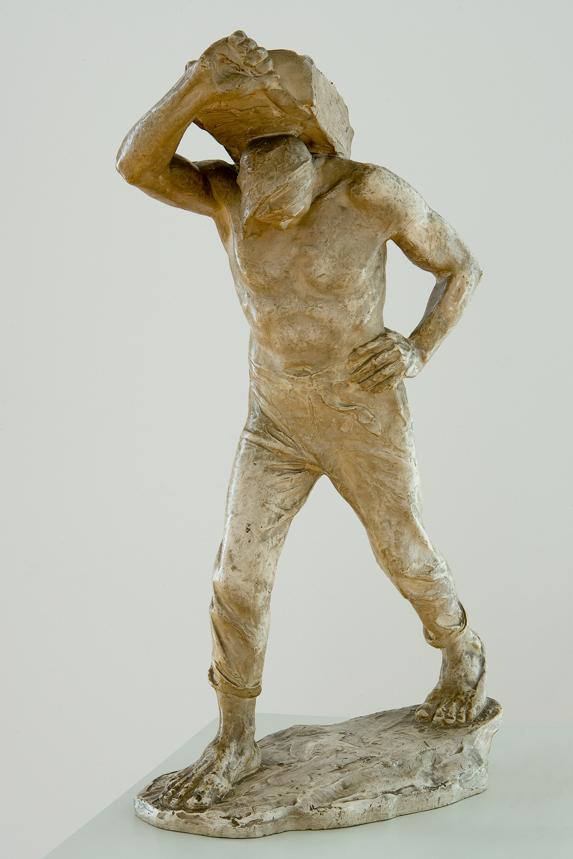 Skulptur Der Lastträger von Constantin Meunier, entstanden um 1889. Die Skulptur stellt einen Mann dar. Der Mann geht und trägt etwas auf seinen Schultern.