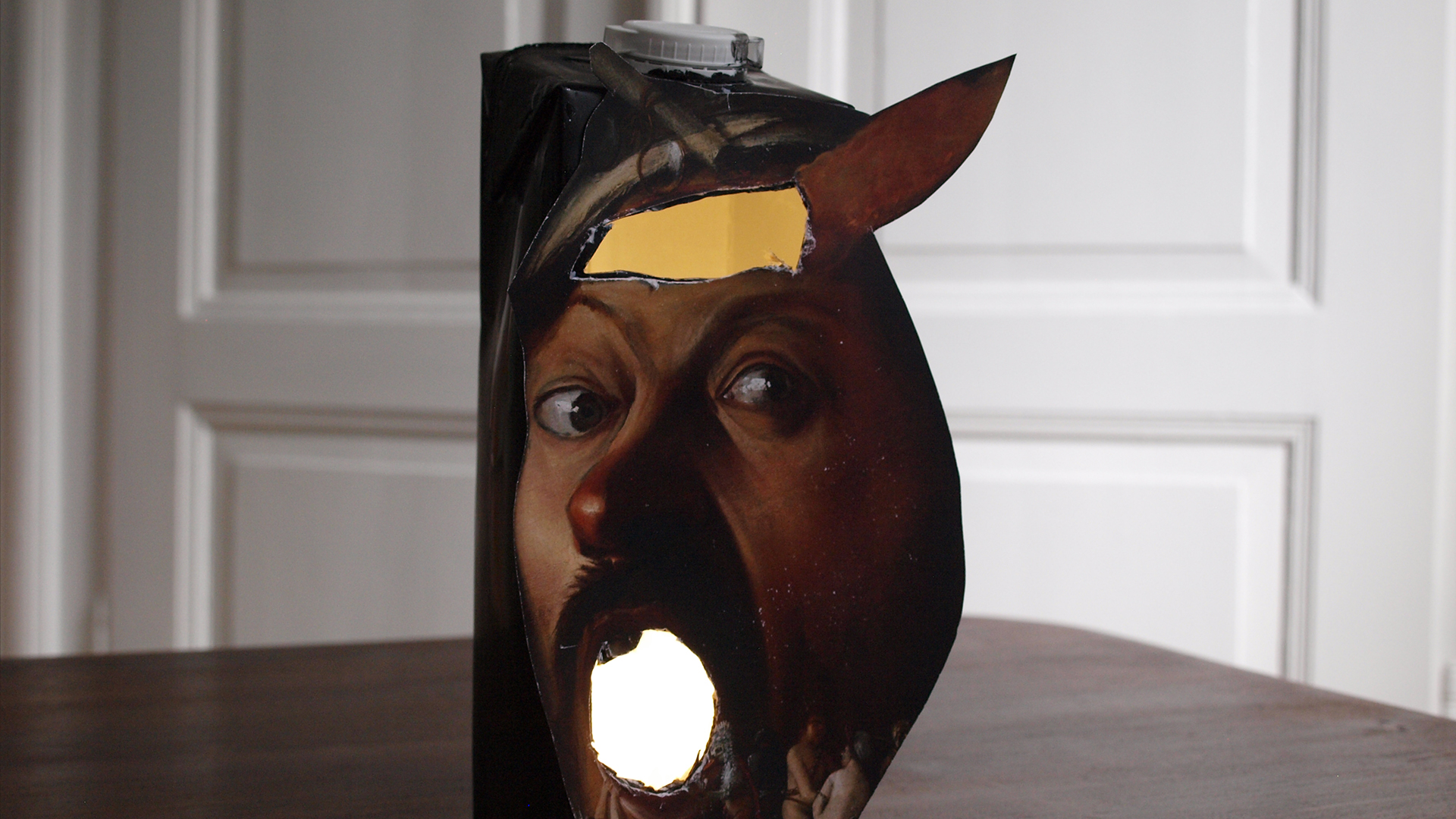Das fertige Tetrapack-Spuklicht. Es zeigt den Kopf eines Mannes mit einer Lichtöffnung für das Teelicht.