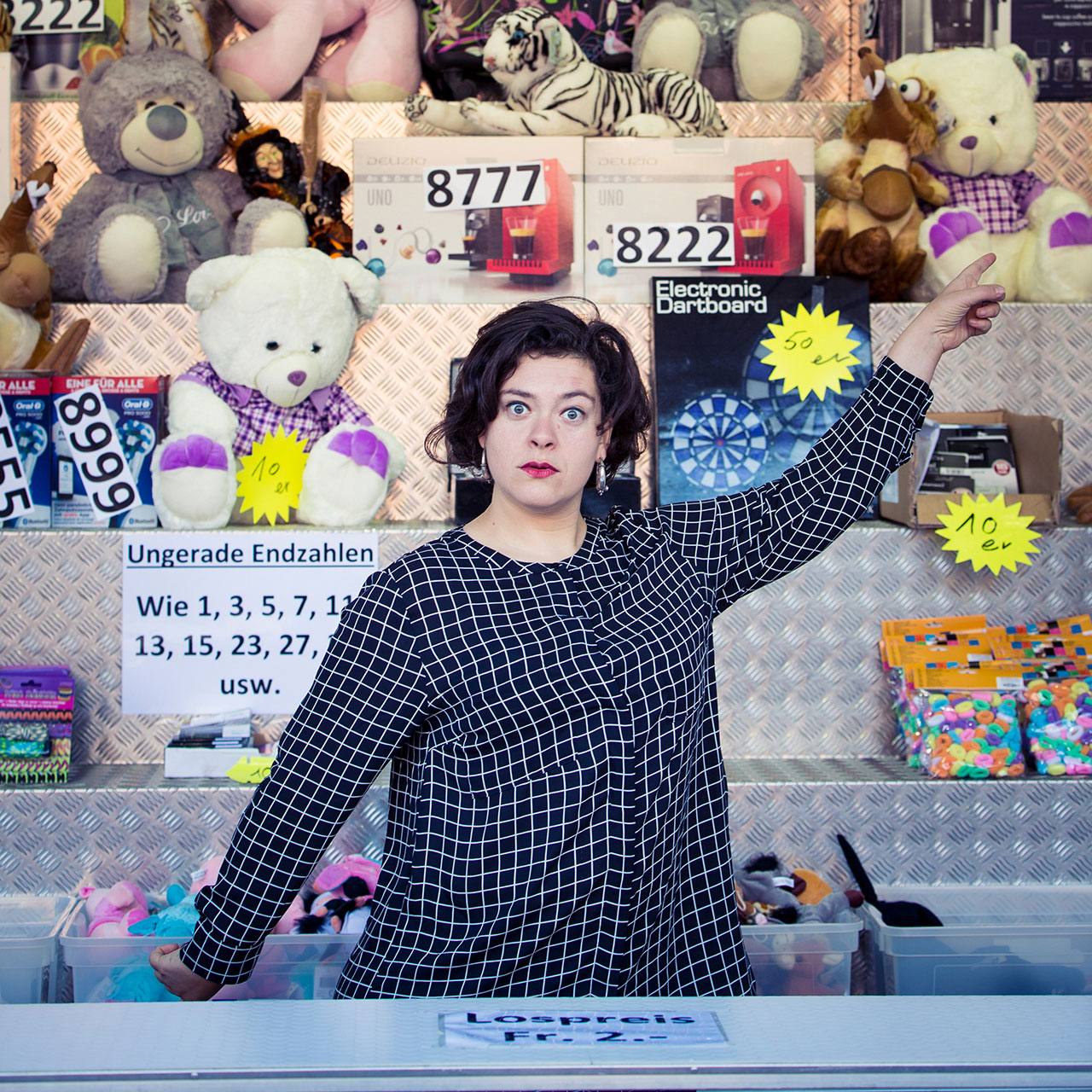 Porträt der Autorin Nora Gomringer, wie sie vor einer Wand mit Spielzeug und Stofftieren steht.