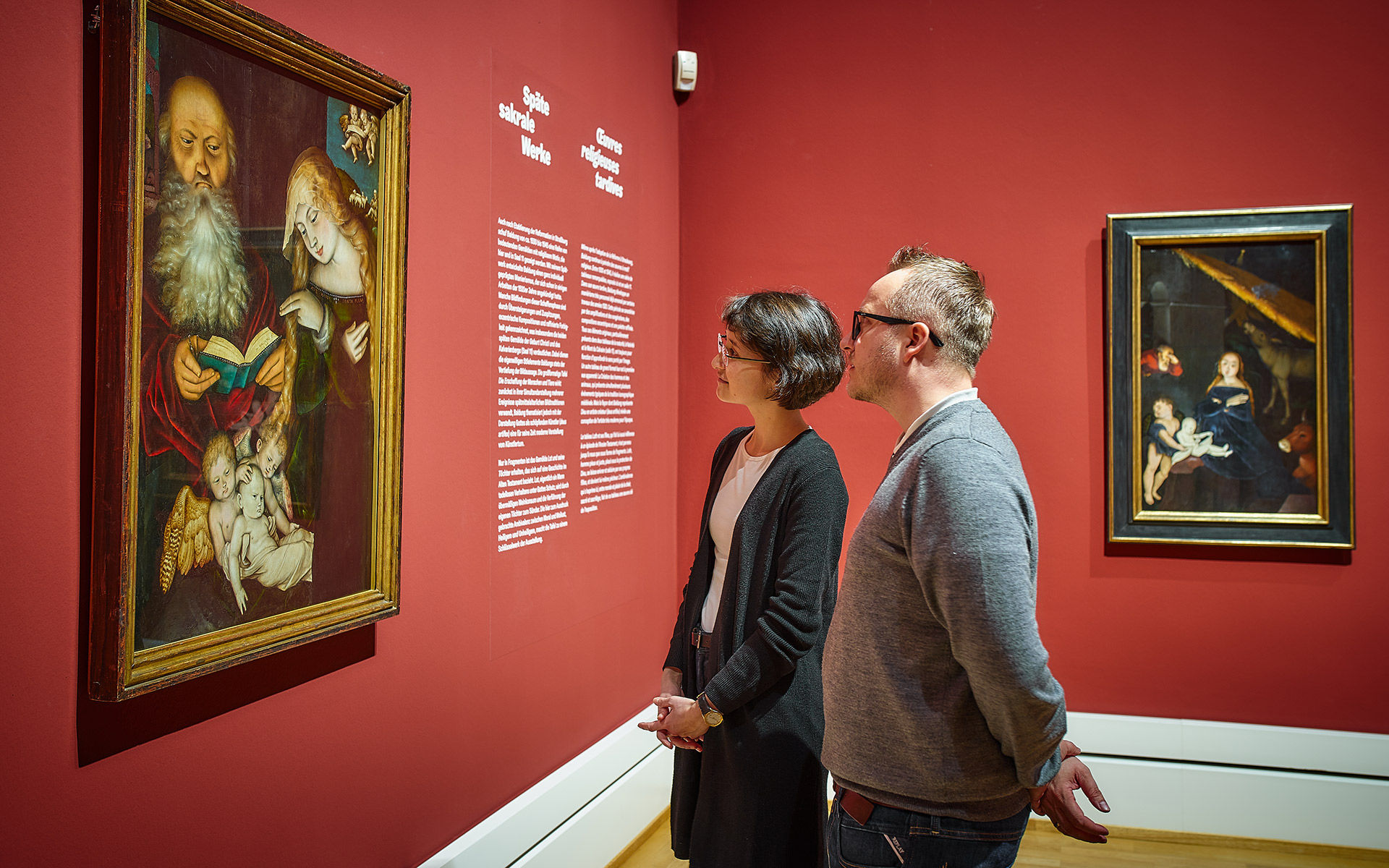 Zwei Besucher*innen der Ausstellung Hans Baldung Grien betrachten Baldungs Gemälde "Geburt Christi".
