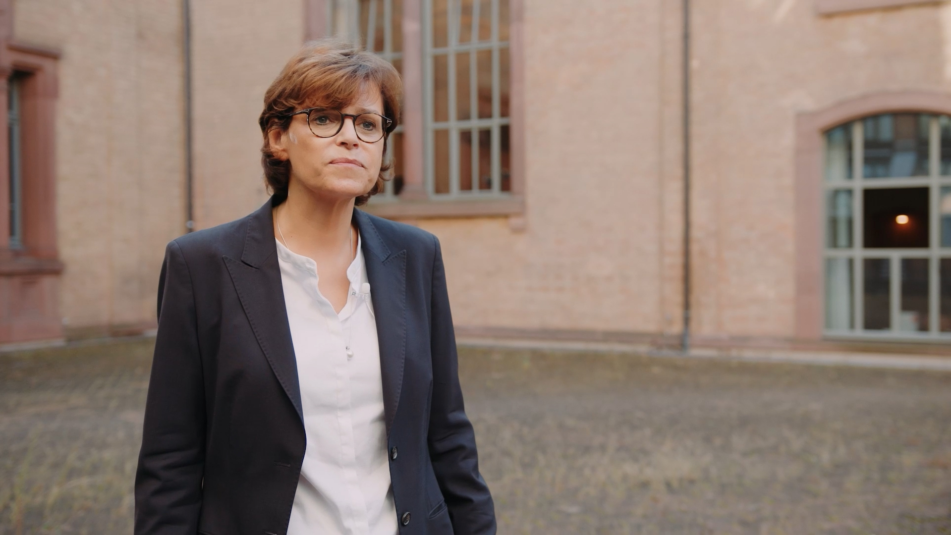 Porträt von Prof. Dr. Pia Müller Tamm. Sie steht im Innenhof der Kunsthalle und trägt einen dunkelblauen Blazer.