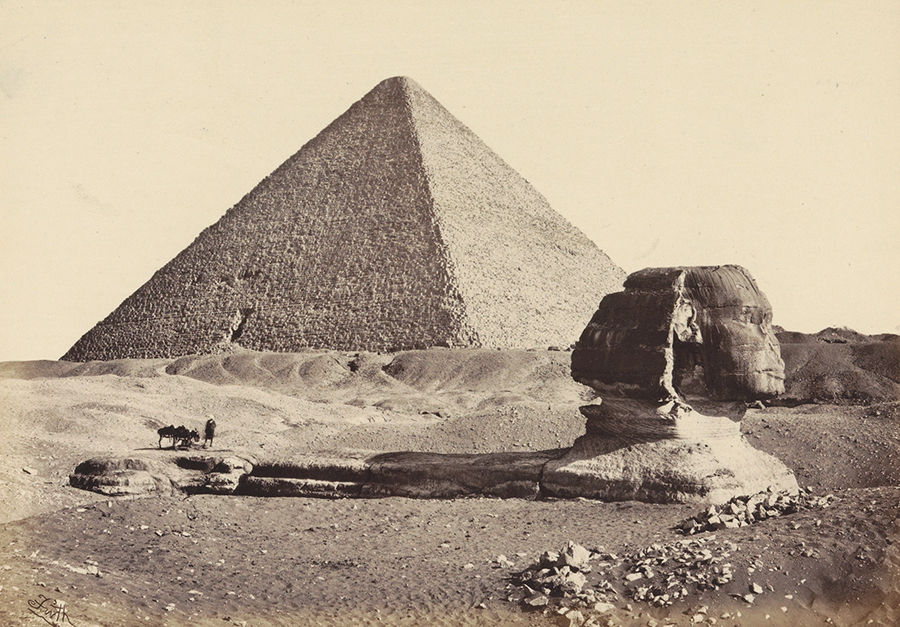 Abbildung der Sepia-Fotografie "Sphinx und Große Pyramide in Gizeh" von Francis Frith. Sie zeigt den Kopf der Sphinx im Sand versunken und im Hintergrund die Pyramide.