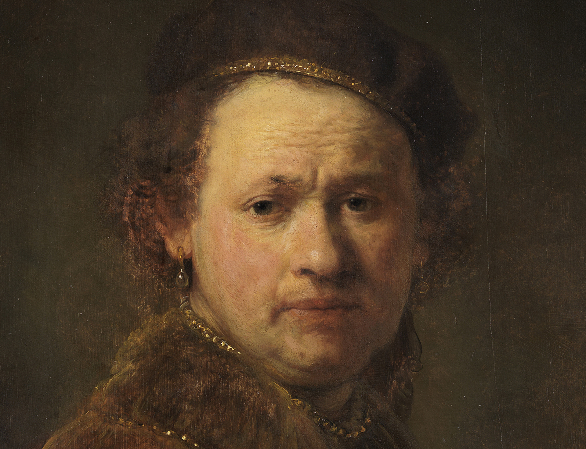Detail of Rembrandt's self-portrait: The artist‘s face with the slightly wrinkled forehead is illuminated from the left.