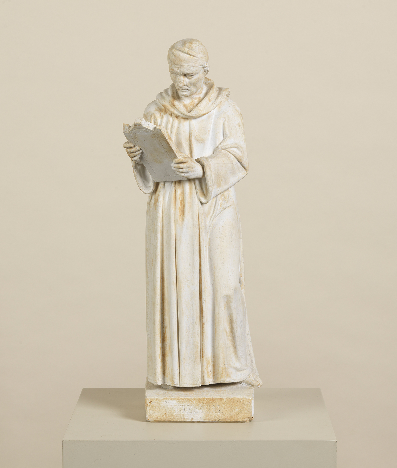 Das Kunstwerk zeigt den italienischen Renaissance Künstler Fra Giovanni Angelico. Der Maler steht aufrecht, hält eine Tafel in der Hand und betrachtet diese. Die Skulptur stammt von dem Bildhauer Ludwig Schwanthaler.