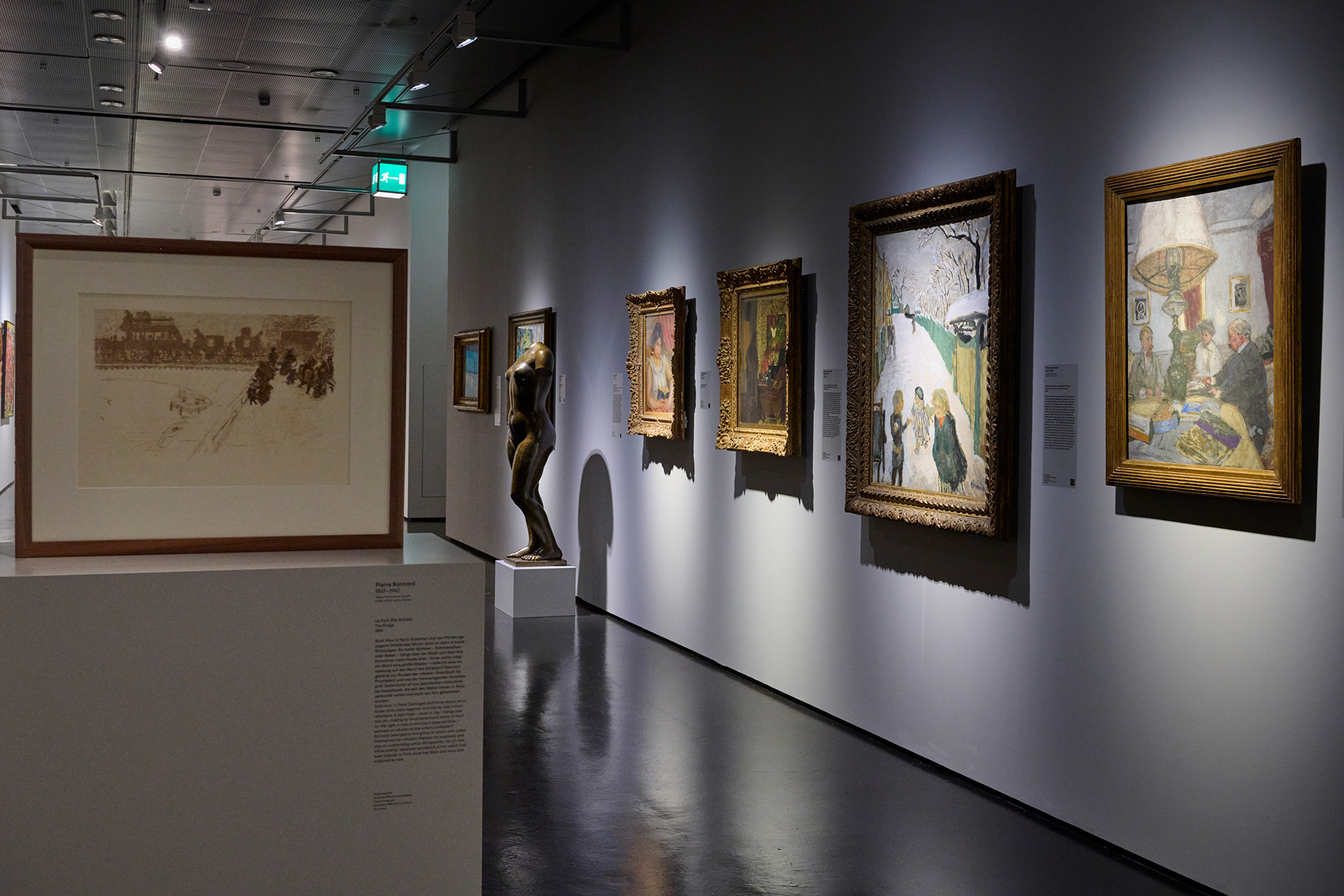 Foto eines Ausstellungsraumes mit verschiedenen Gemälden an der Wand.