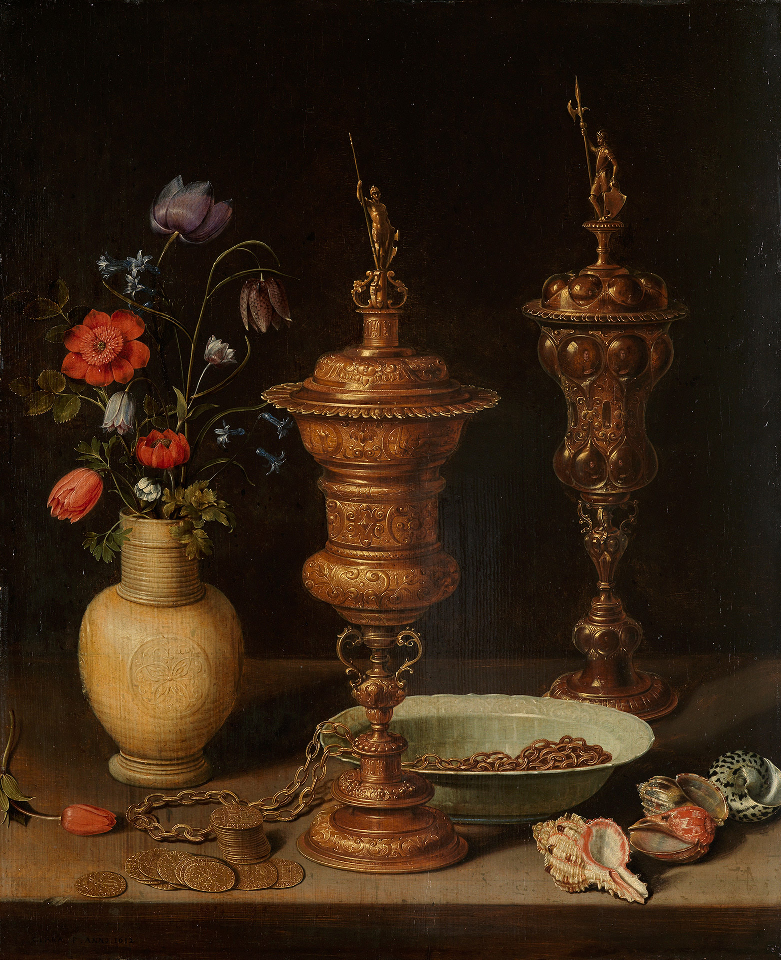 Abbildung des Stilllebens mit Blumen und Goldpokalen von Clara Peeters. Zwei prunkvolle Goldpokale stehen auf einem Tisch. Daneben eine Vase mit bunten Blumen. Auf dem Tisch liegen Muscheln, Münzen und eine Schale.