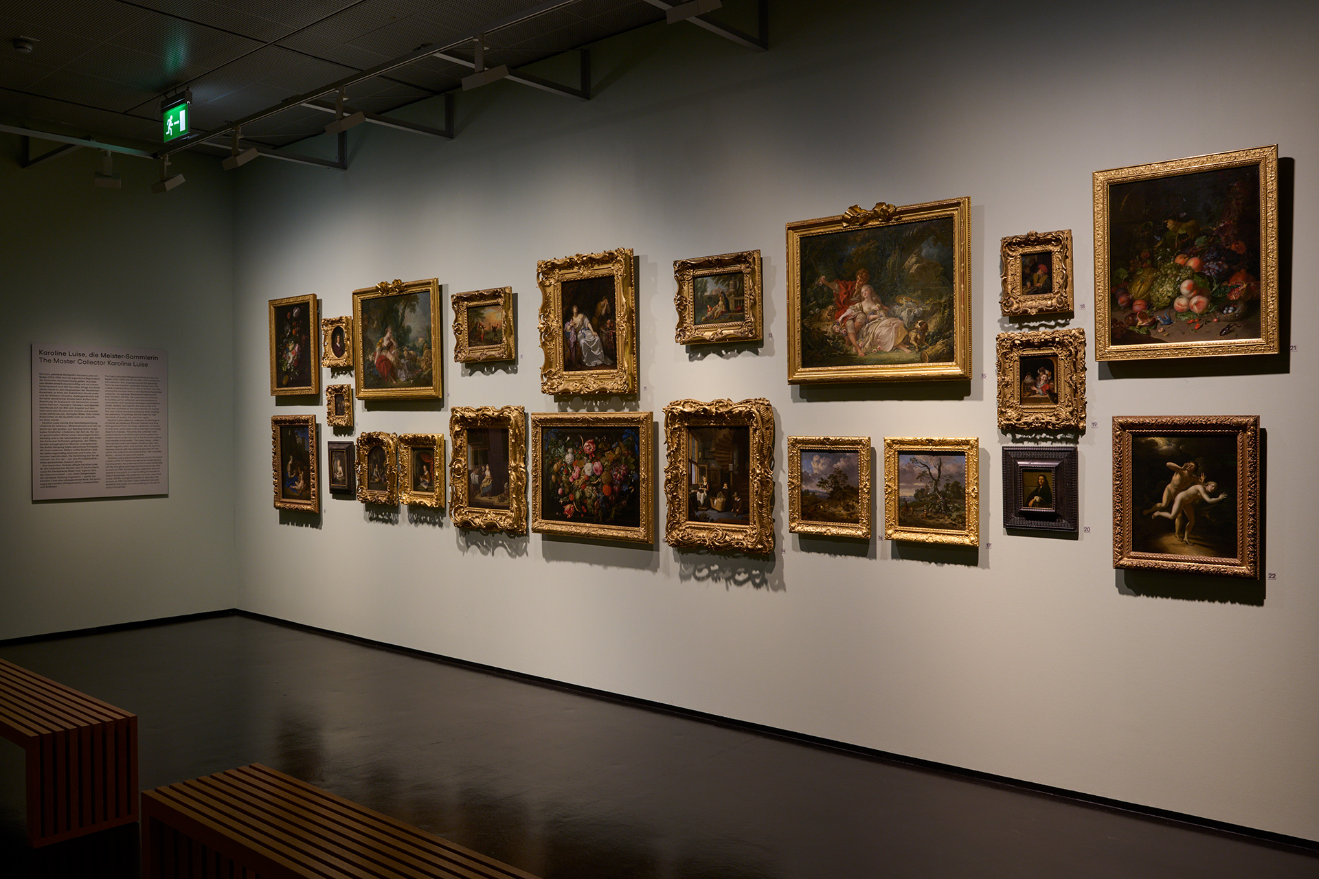 Ausstellungsansicht mit barocker Hängung in der Kunsthalle Karlsruhe. An der Wand hängen verschiedene Gemälde in goldenen Rahmen.