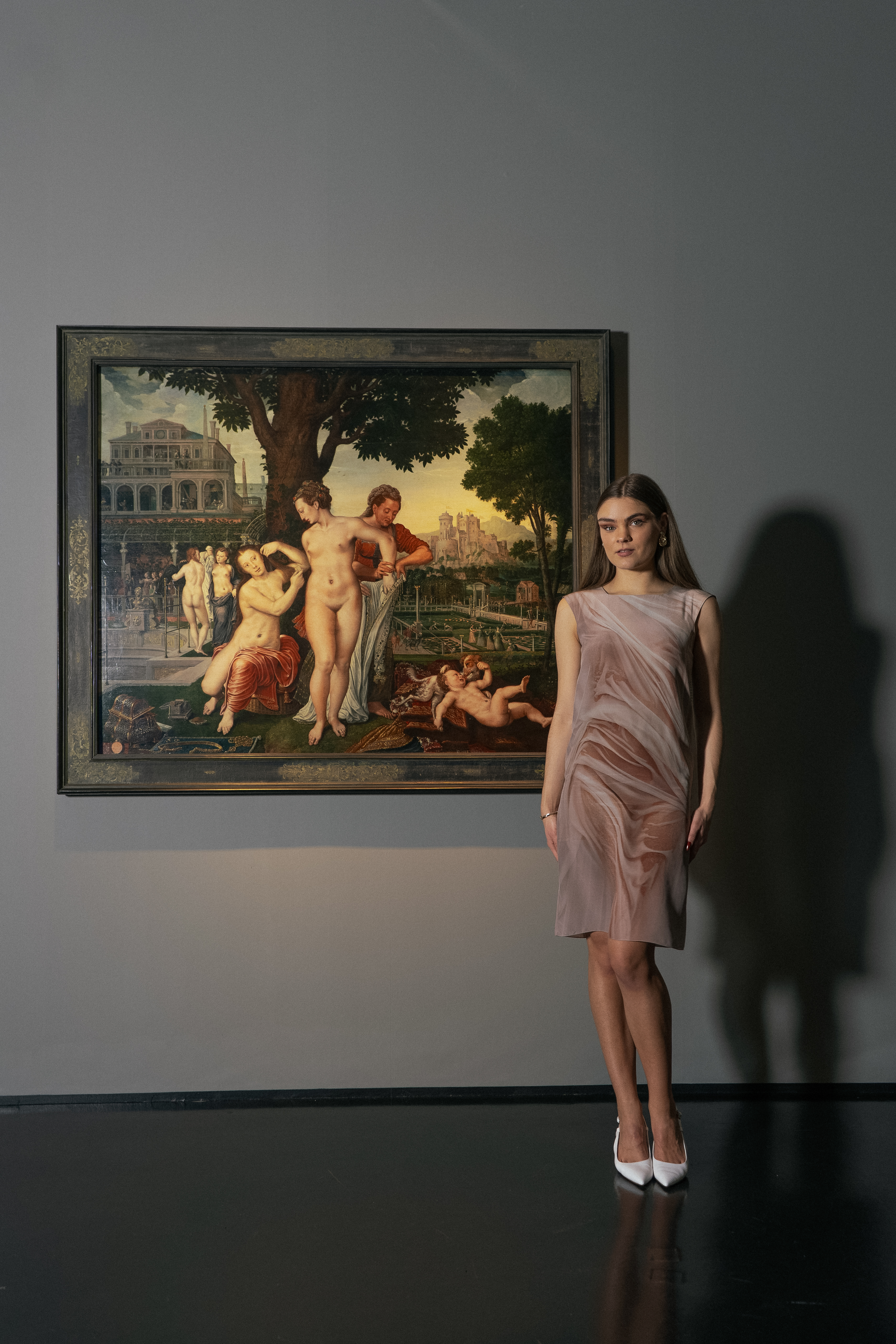 Eine Frau in einem apricotfarbenen Kleid und weißen Pumps neben dem Kunstwerk "Bathseba".