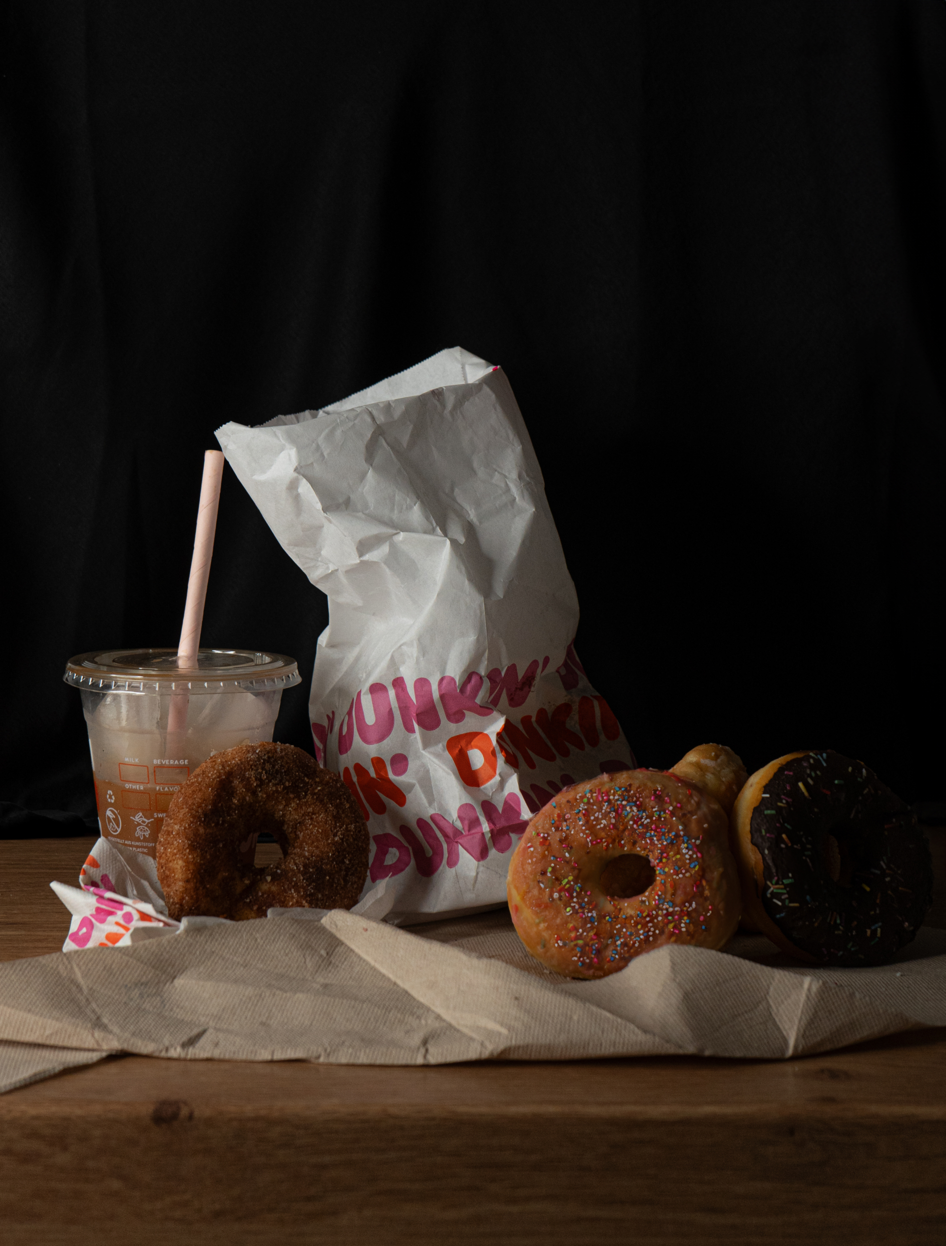 Ein Stillleben auf dem Donuts, eine Tüte und ein Getränk sind.
