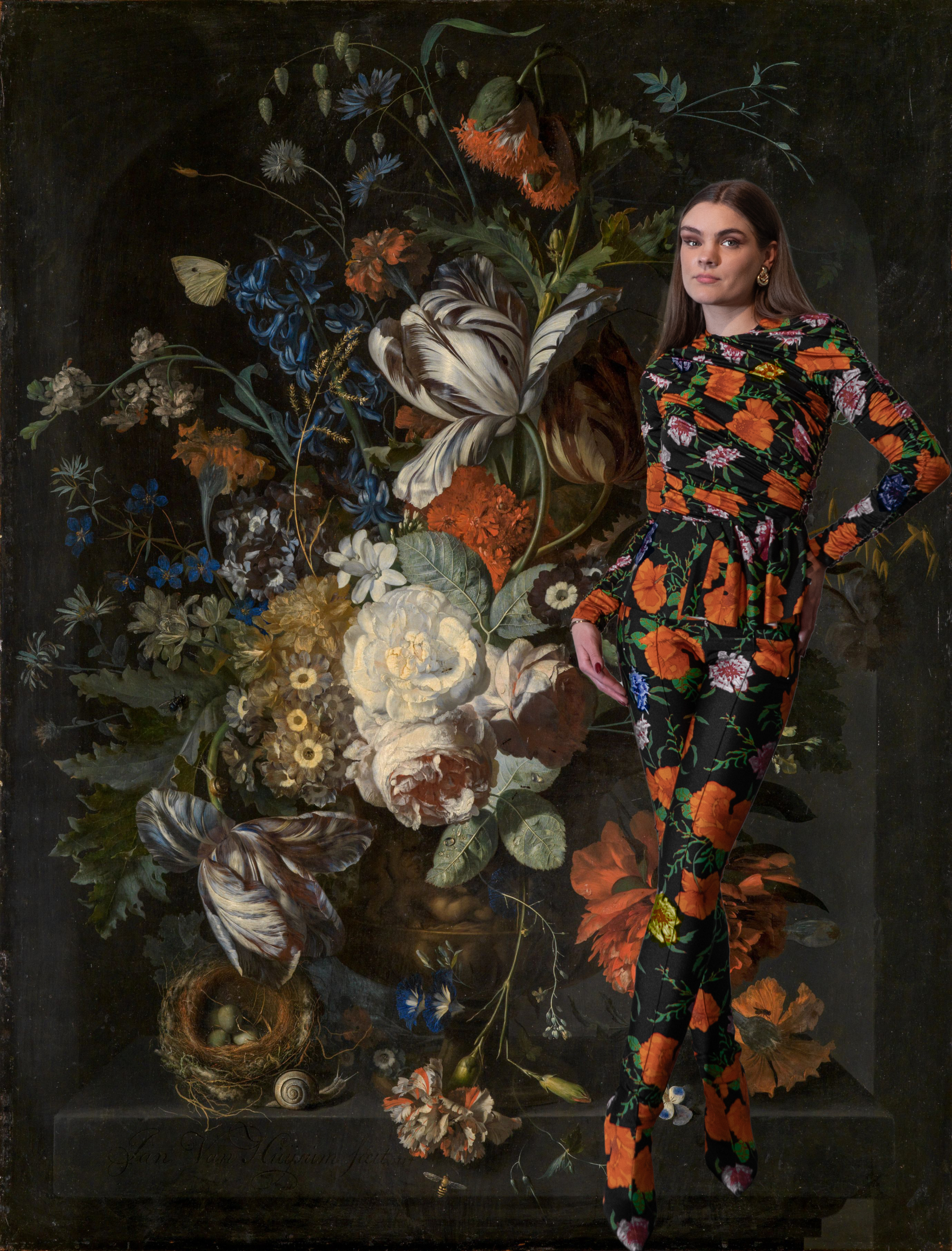 Eine Frau in einem mit Blumen versehenen Zweiteiler in einem bunten Blumenstillleben.