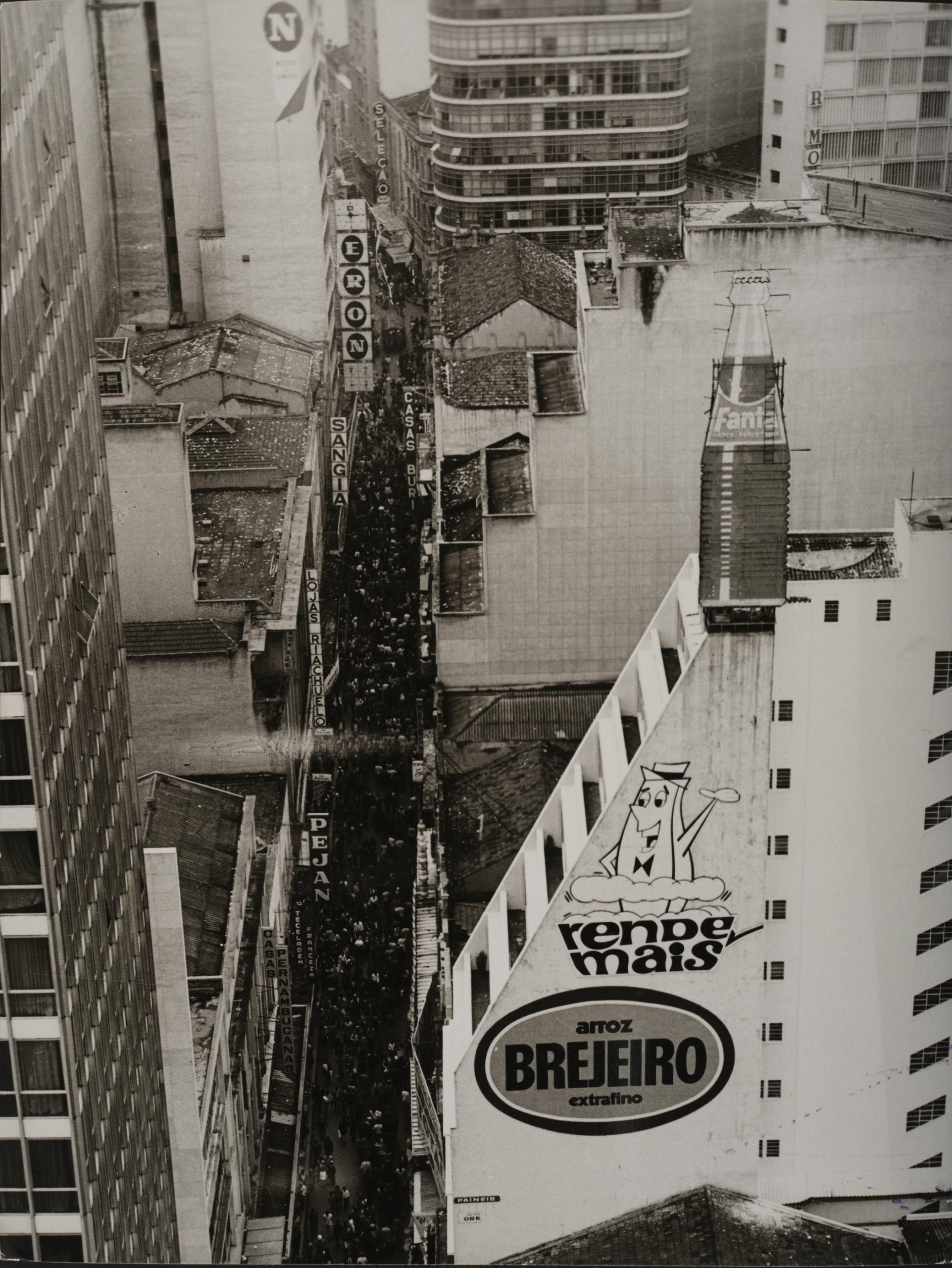 Die Fotografie gibt einen Blick aus einem hohen Gebäude frei, hinab in die Stadt auf Gebäude und Menschenvolle Straßen.