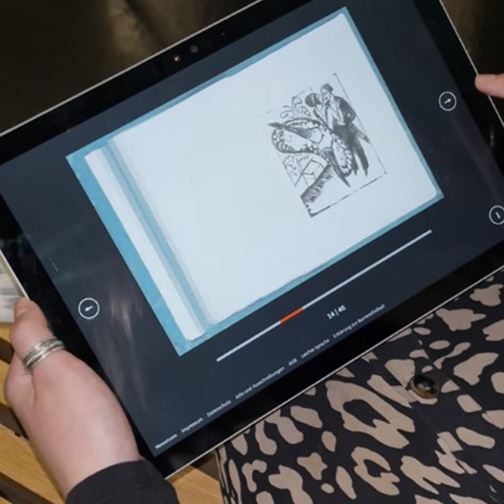 Eine Person hält ein iPad in den Händen auf dem ein Katalog mit Skizzen von Ernst Ludwig Kirchner zu sehen sind, durch die man sich digital durchblättern kann.