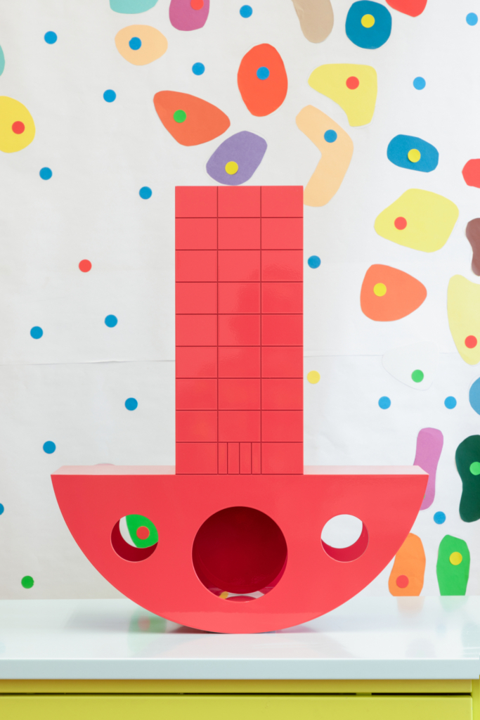 The colorful architectural model can move when blown on. Its base is a semicircle from which a tower rises.