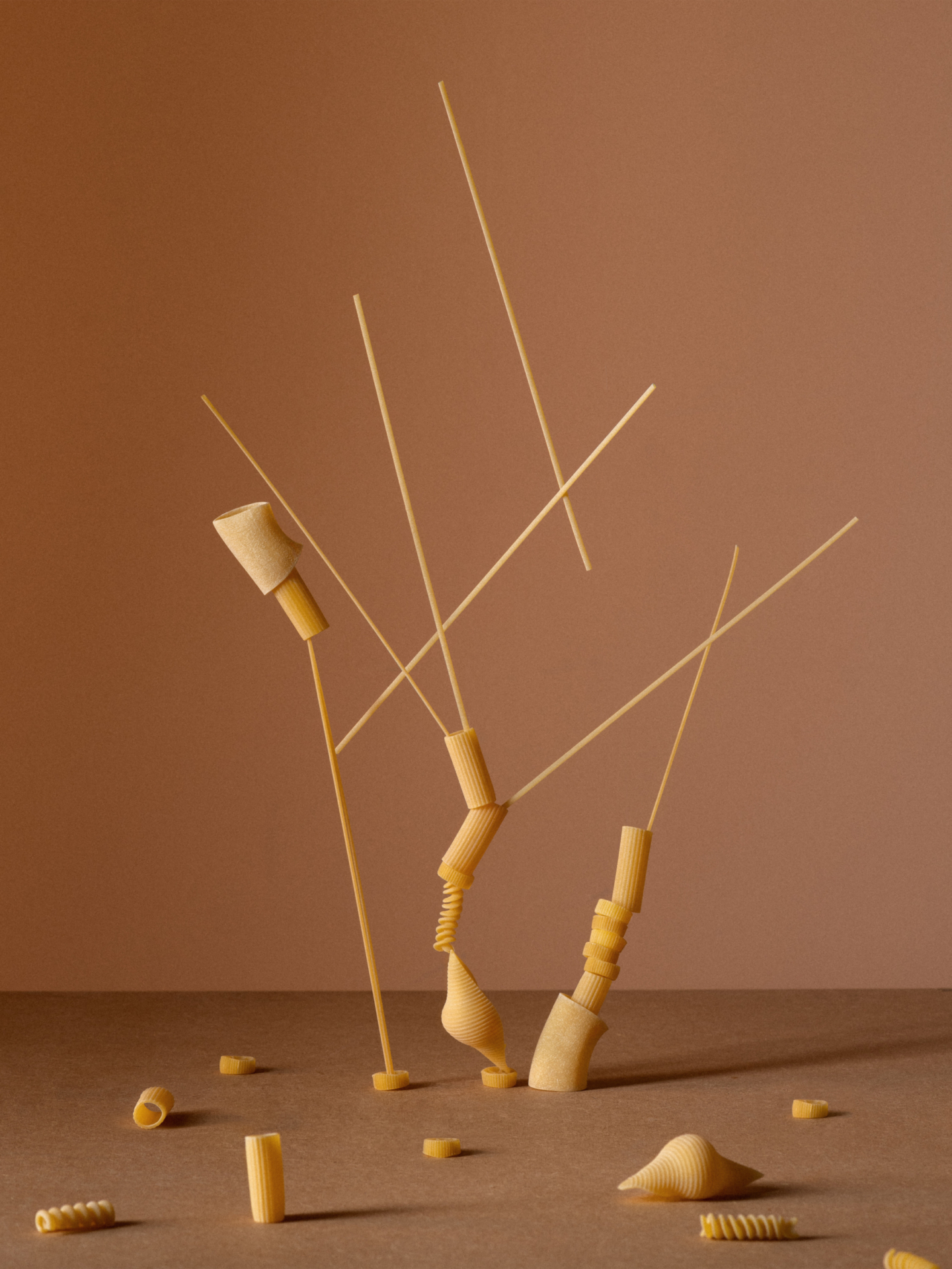 Die zwölf einzelnen Fotografien wie in einem Raster angeordnet. In jedem Bild wird ein Lebensmittel oder Hygieneartikel, wie Klopapier oder Eier, zu einem waghalsigen Konstrukt.