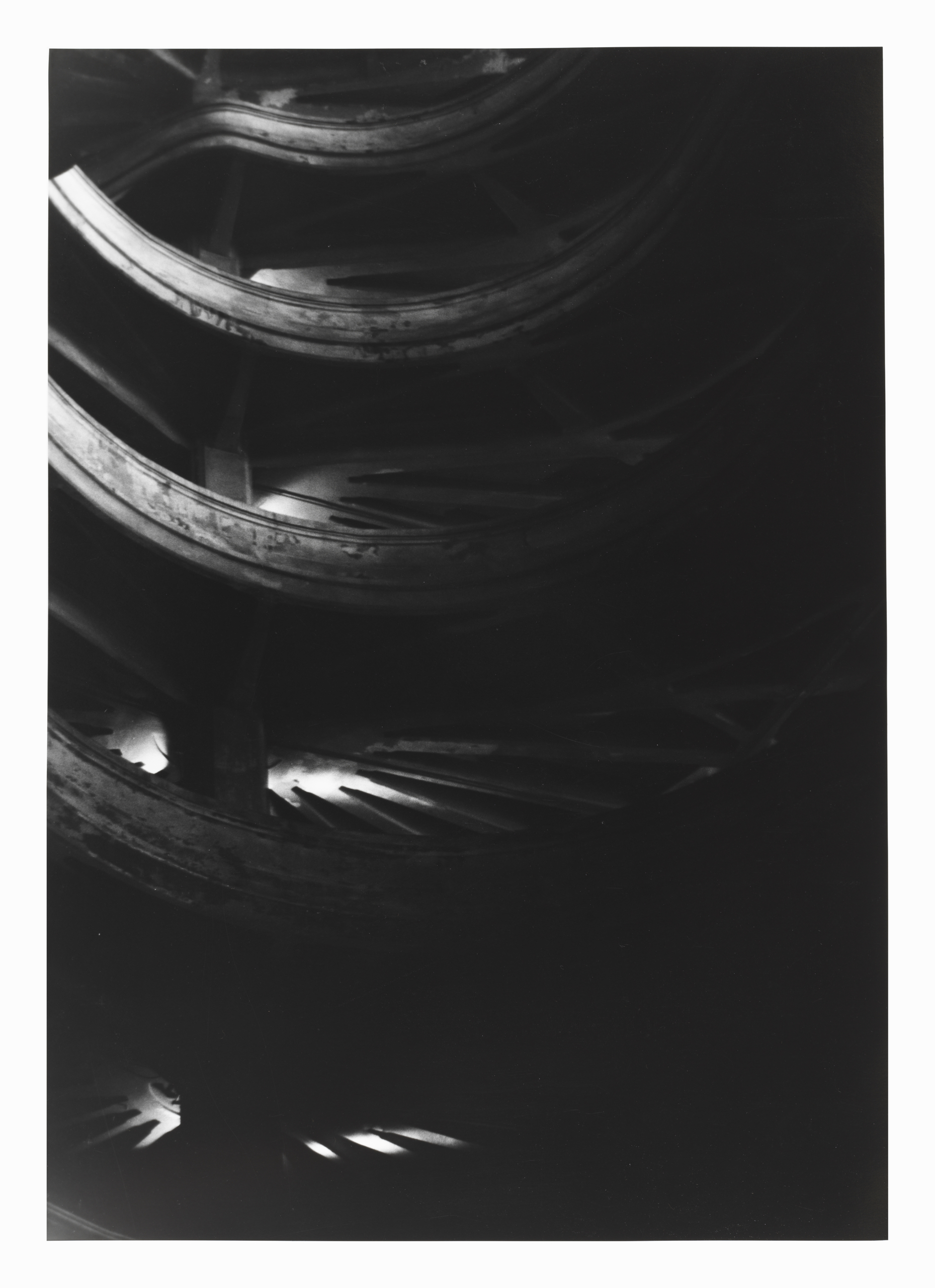 Die Schwawrz-Weiß-Fotografie zeigt ein spiralförmig nach oben strebende Fahrbahn für Autos. Allerdings ist aufgrund der Lichtverhältnisse wenig zu erkennen.