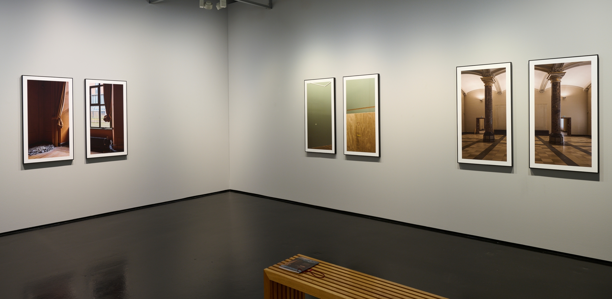 Blick in die Ausstellung Drift mit großformatigen Fotoarbeiten, die paarweise in schwarzen Rahmen an grauen Wänden hängen und die leeren Innenräume des historischen Gebäudes der Kunsthalle zeigen.