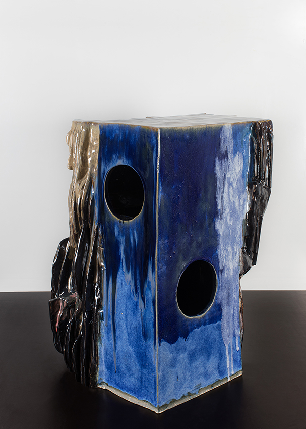 Eine ca. 50 cm hohe Skulptur steht auf dem Boden. Sie besteht aus unterschiedlichen zusammengesetzten Formen. Ihre Oberfläche ist teilweise glatt oder rau.