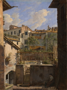 Man blickt auf einen Hinterhof. Eine Frau mit ihrem Kind sitzt im Schatten. An den Hinterhof schließt ein kleiner Garten, der von vielen unterschiedlich hohen Häusern umgeben ist.