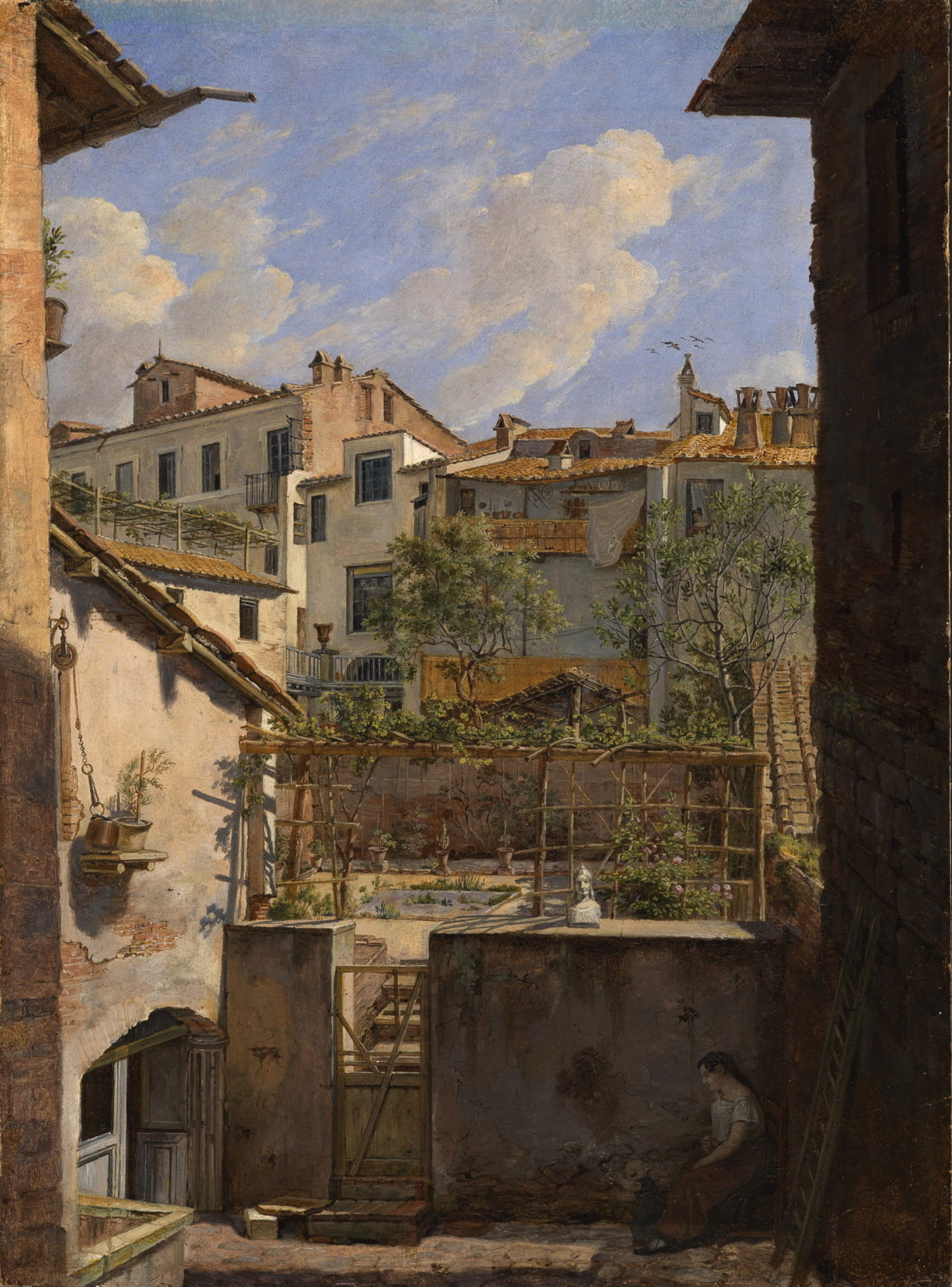 Man blickt auf einen Hinterhof. Eine Frau mit ihrem Kind sitzt im Schatten. An den Hinterhof schließt ein kleiner Garten, der von vielen unterschiedlich hohen Häusern umgeben ist.